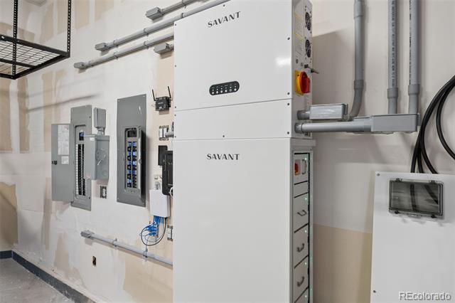 Utility room with Savant home automation equipment, electrical panels, and exposed conduit.