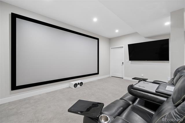Home theater with a large projection screen and black leather reclining seats.
