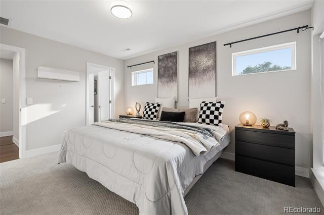 Staged bedroom with a large white bed, checkered pillows, and a dark dresser.