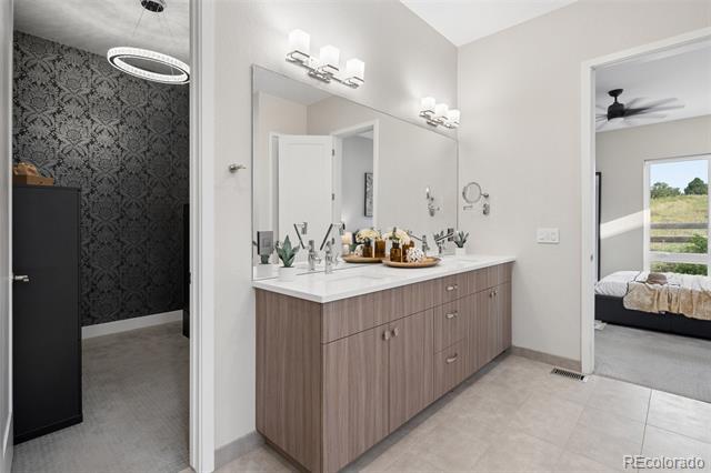 Bathroom with a long double-sink vanity, large mirrors, and a view into the adjoining bedroom.