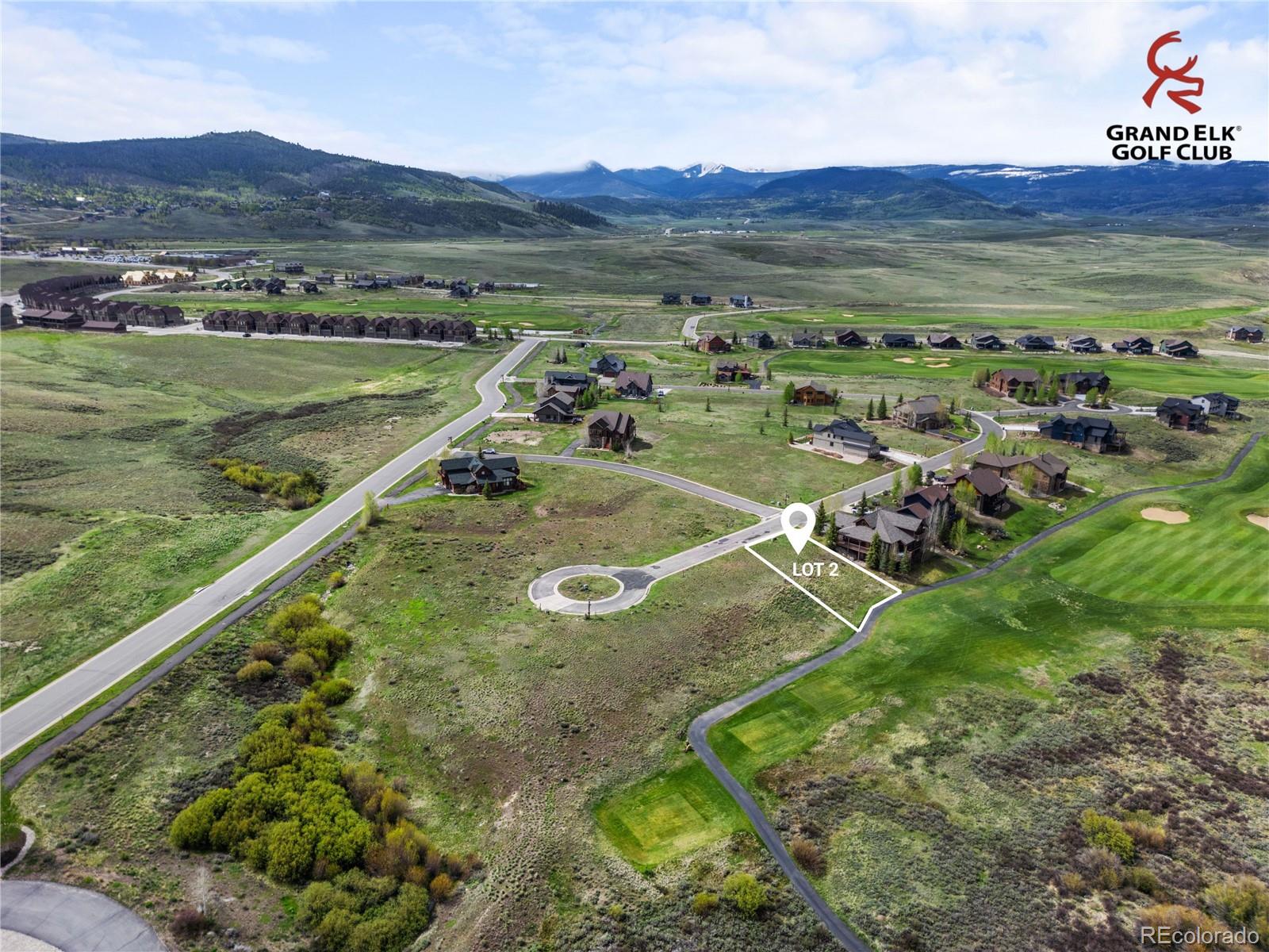 Aerial view of vacant Lot 2 beside homes and golf course, with a mountain valley beyond.