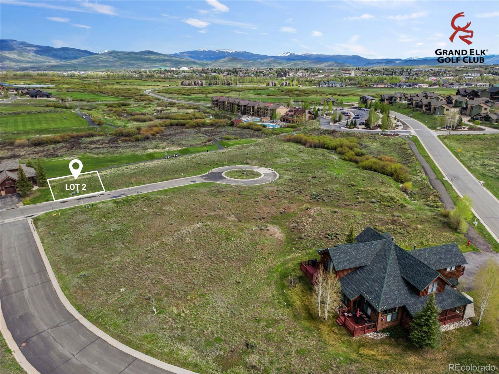 Vacant Lot 2 beside a curved street, with Grand Elk Golf Club and mountain ranges in the distance.