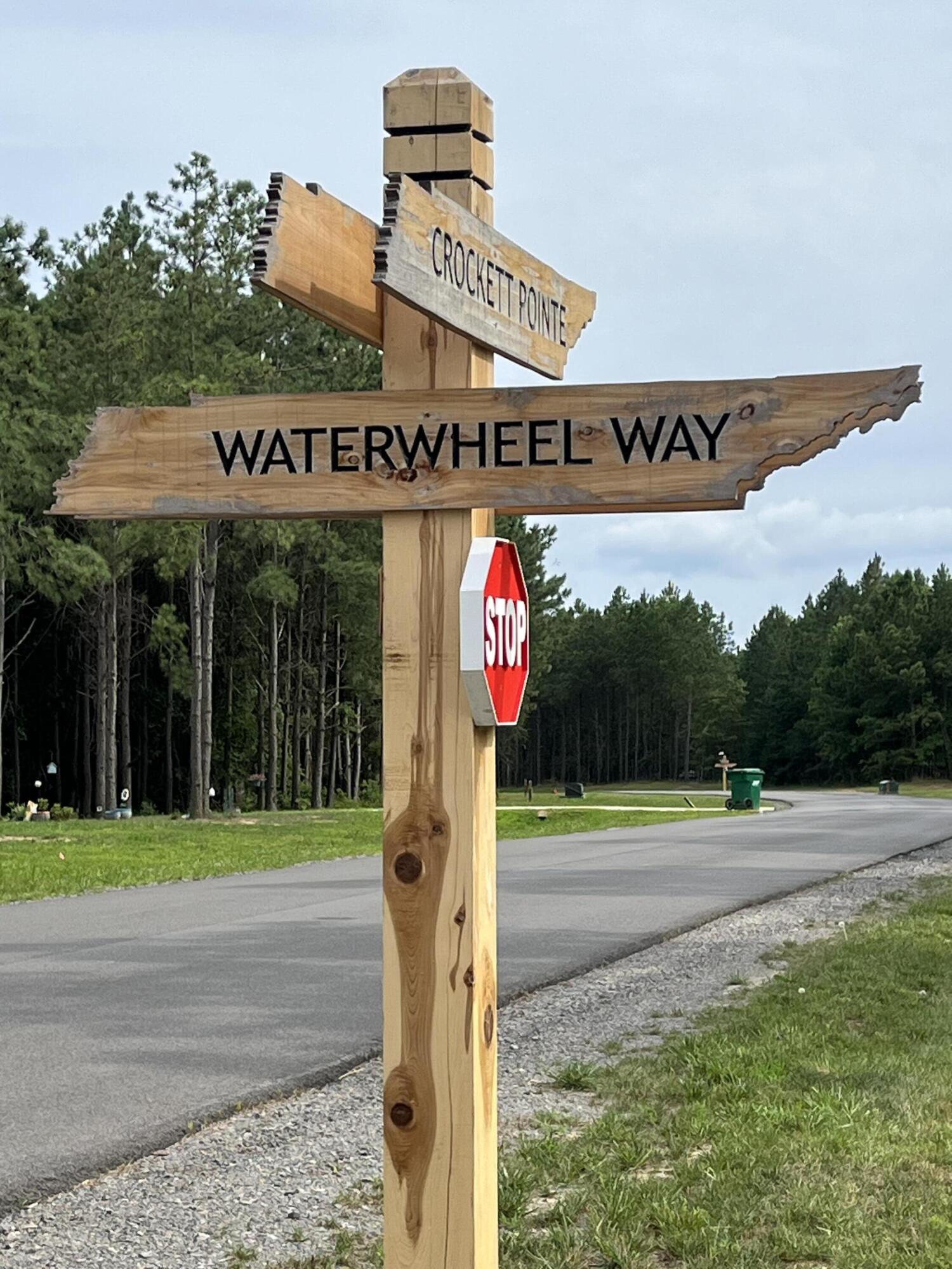 Wooden Crockett Pointe and Waterwheel Way street signs beside a wooded neighborhood road.