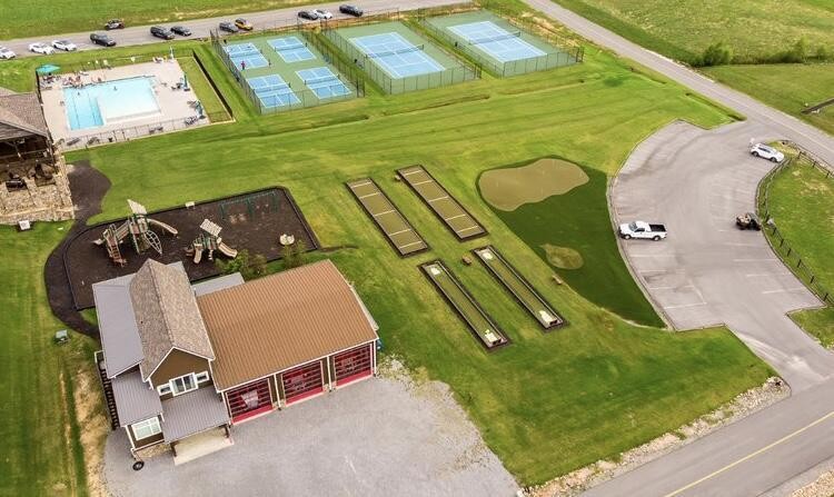 Aerial view of a recreation complex with tennis courts, a swimming pool, and a playground.