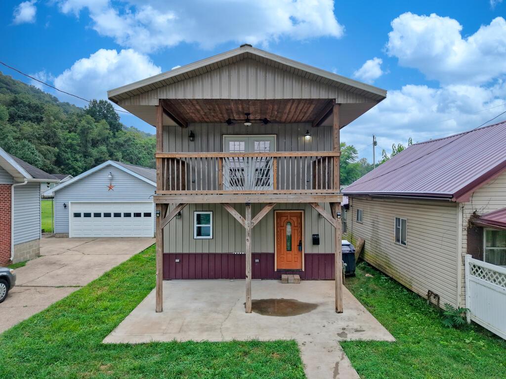 Home with a raised wooden balcony and covered concrete parking area.