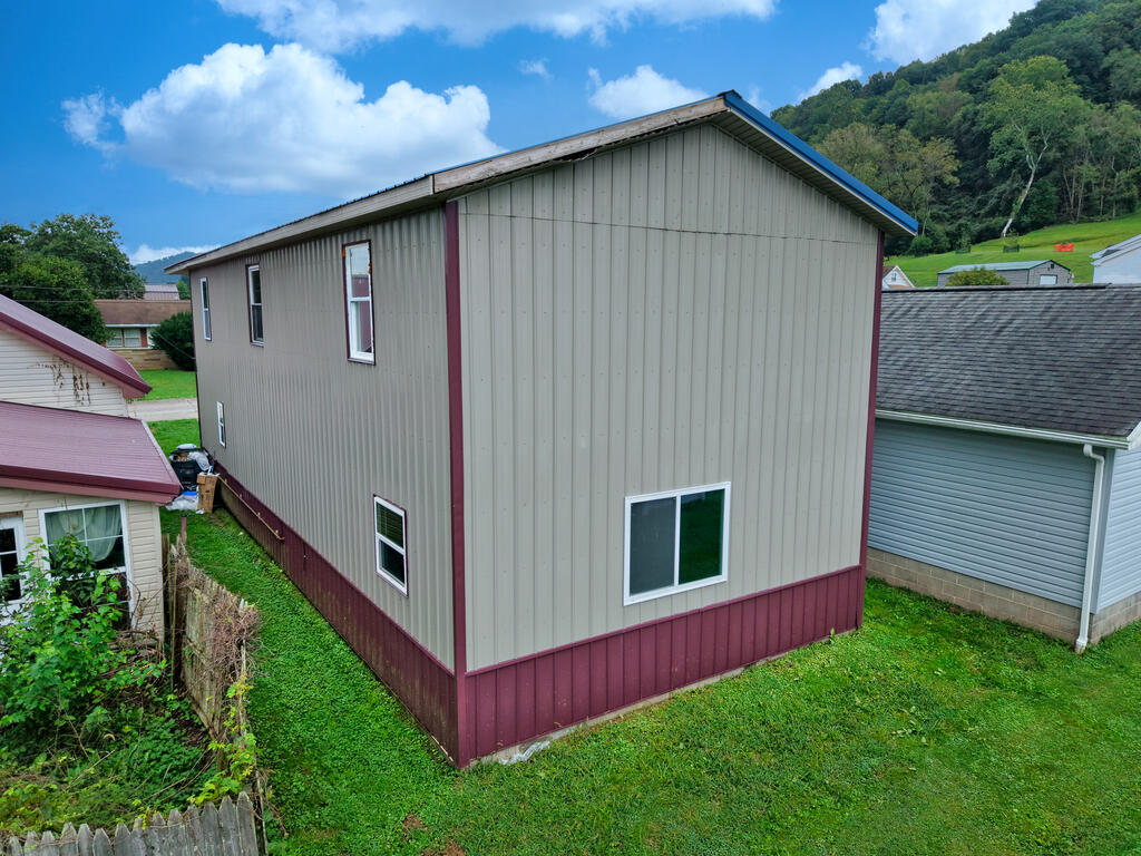Tall two-story gray metal-sided building with burgundy trim and a grassy yard.