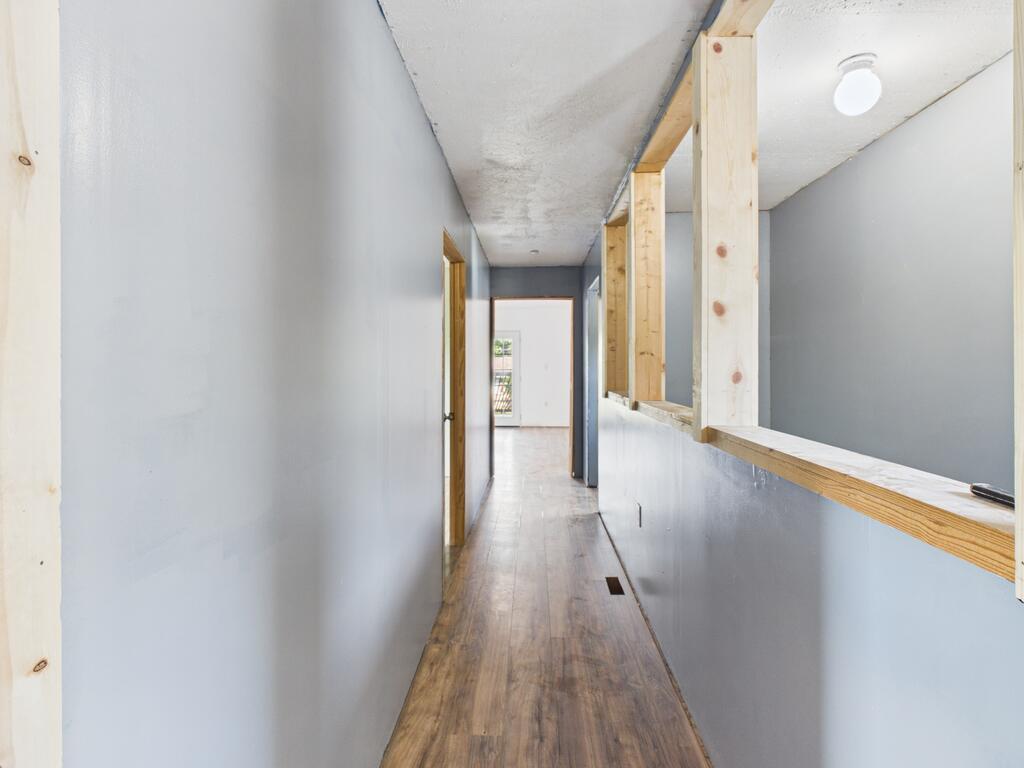 Hallway with wood-look flooring and exposed framing around a pass-through.