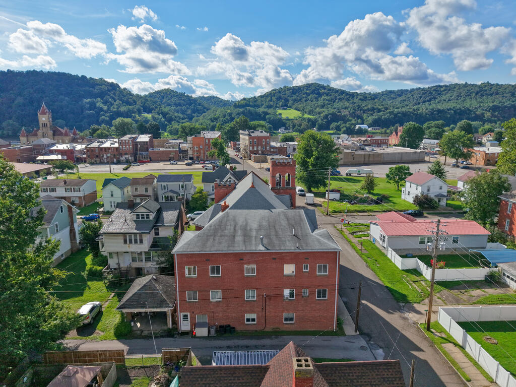 Aerial view of a small town with downtown buildings and wooded hills in the distance.