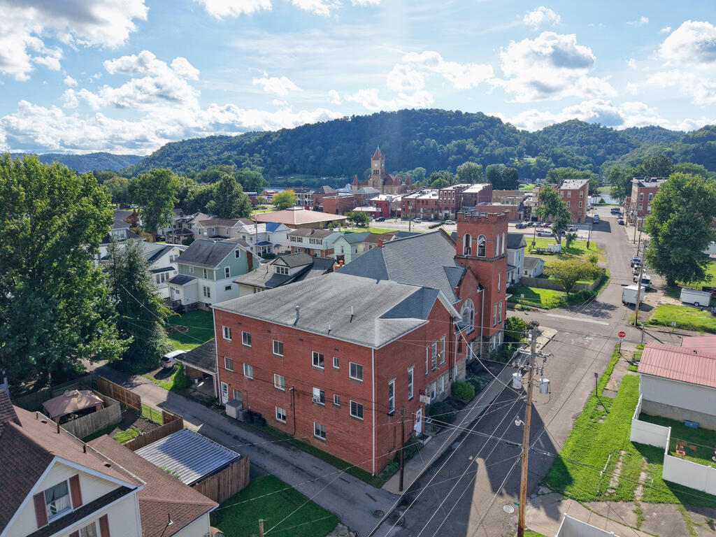 Aerial view of downtown buildings, residential streets, and wooded hills.