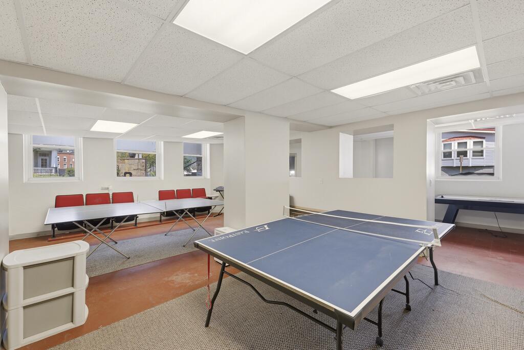 Recreation room with a blue ping-pong table and folding table with red chairs.