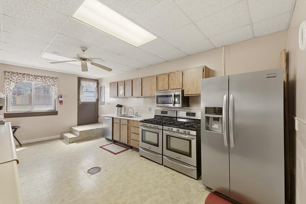 Kitchen with wood-grain cabinets, a large stainless steel refrigerator, and two ranges with ovens.