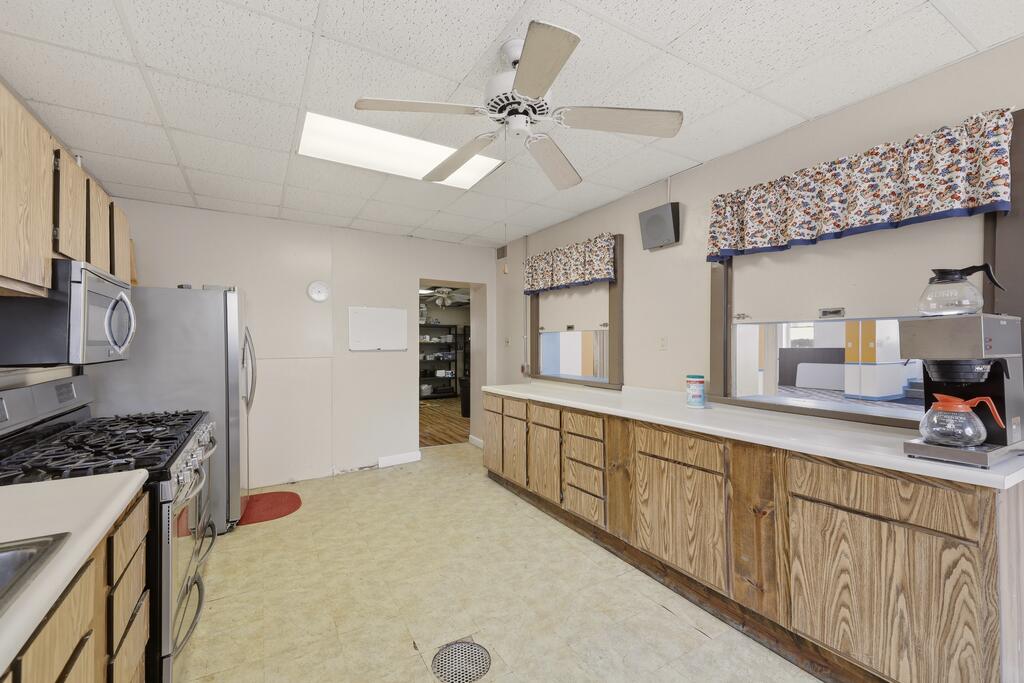 Kitchen with wood cabinets, long countertops, gas range, and pass-through windows.