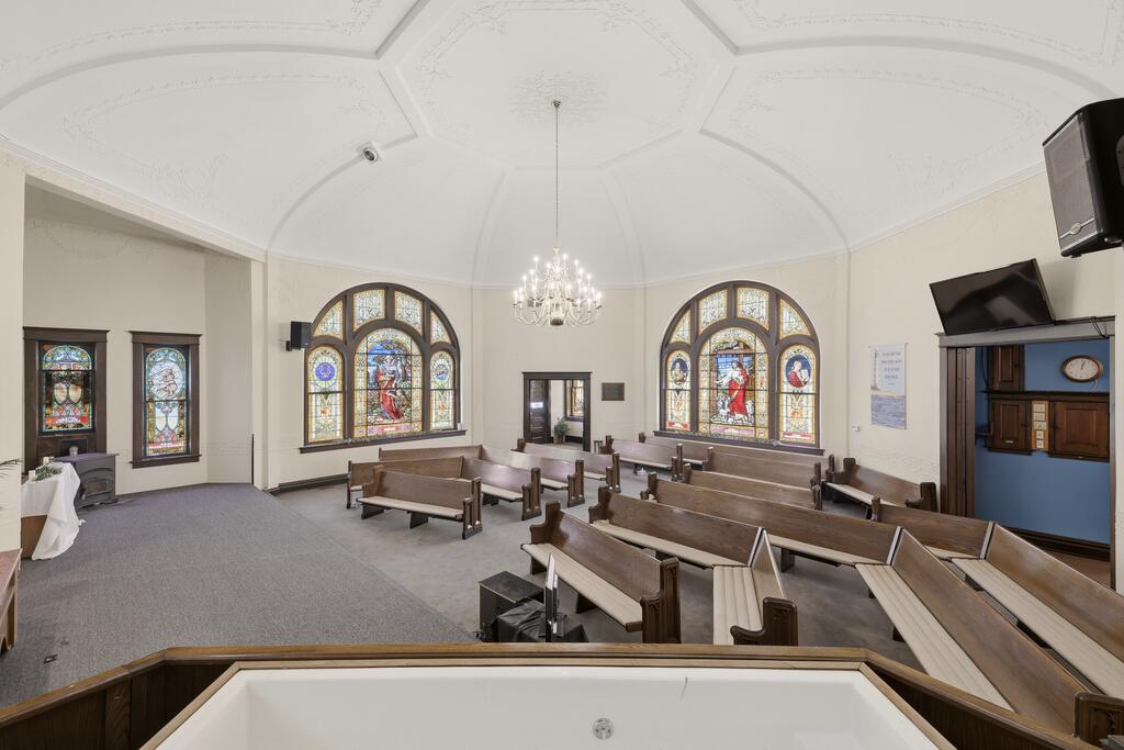 Sanctuary with wooden pews, stained-glass windows, and a chandelier