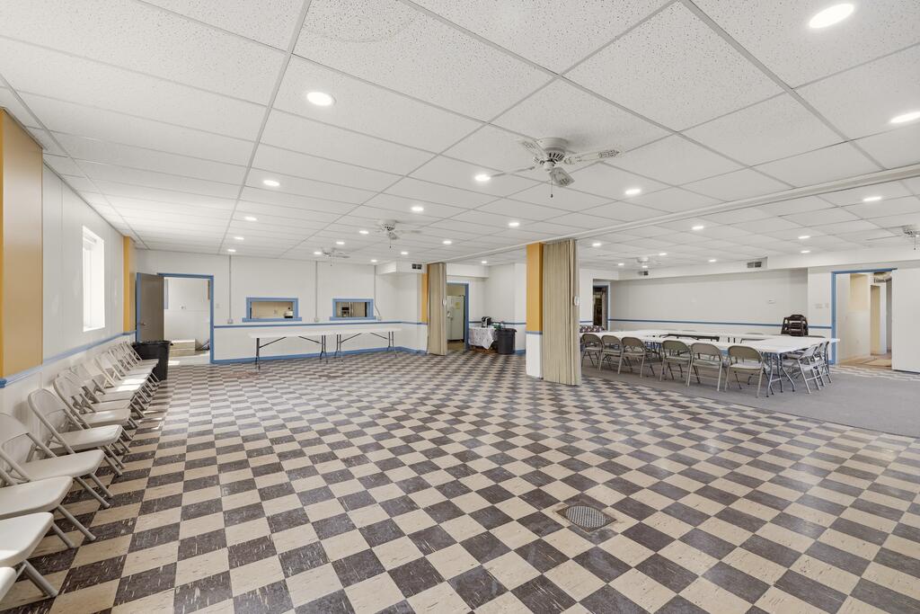 Large meeting room with a checkerboard floor, rows of chairs, and folding tables.