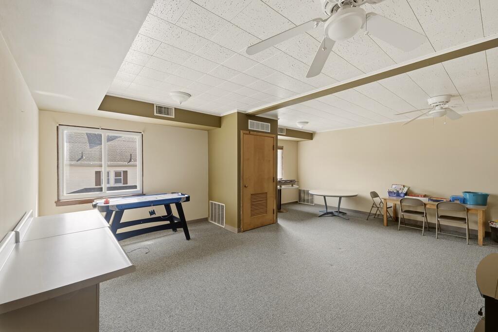 Recreation room with a pool table, folding chairs, and a ceiling fan.