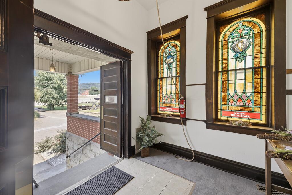 Entryway with two stained-glass windows beside an open front door.