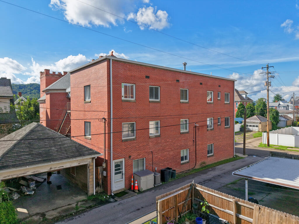 Multi-story red brick building with rows of windows, viewed from above the alley.