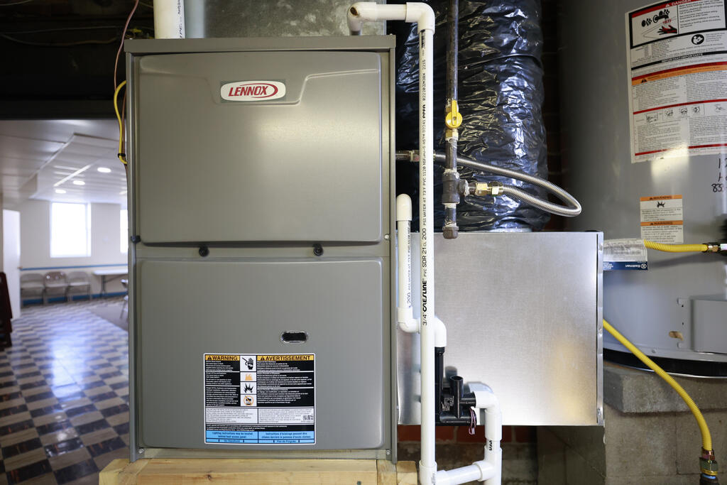 Lennox furnace and HVAC equipment with ductwork and PVC piping in a utility room.