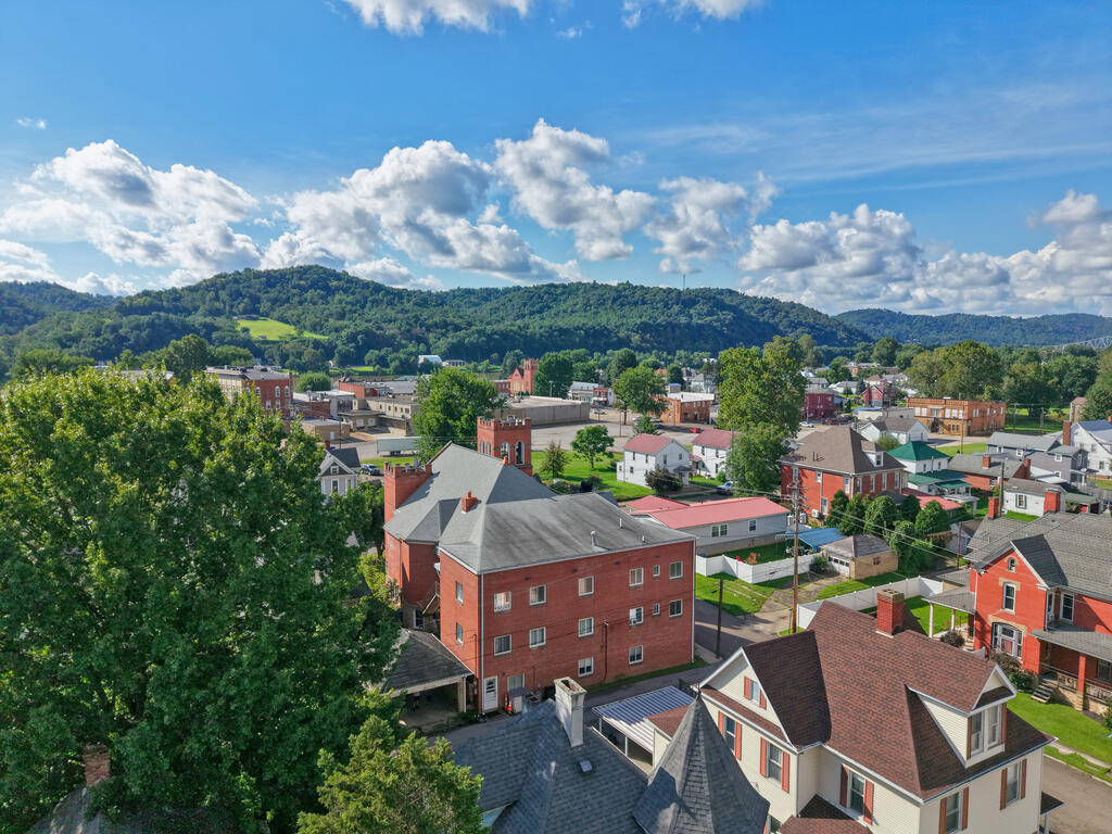 Aerial view of a small town and surrounding wooded hills on a sunny day.