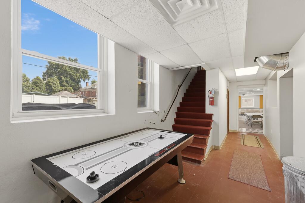 Recreation area with an air hockey table beside carpeted stairs and a hallway.