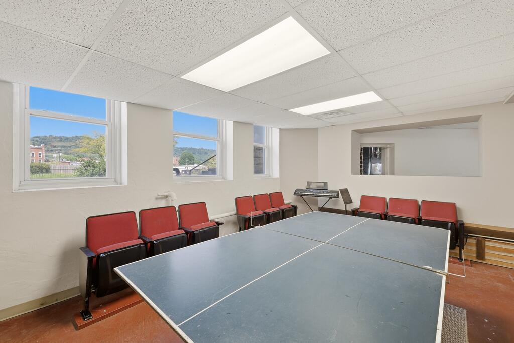 Room with a table tennis table, red chairs, and a keyboard.