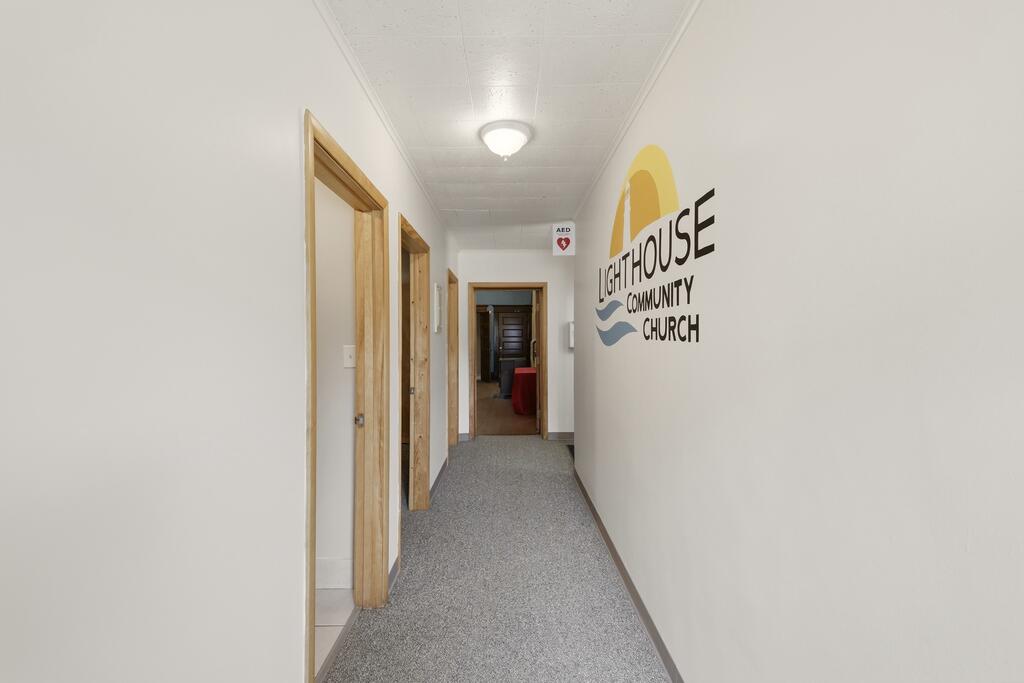Hallway with gray carpet, wood-trimmed doorways, and a Lighthouse Community Church sign.