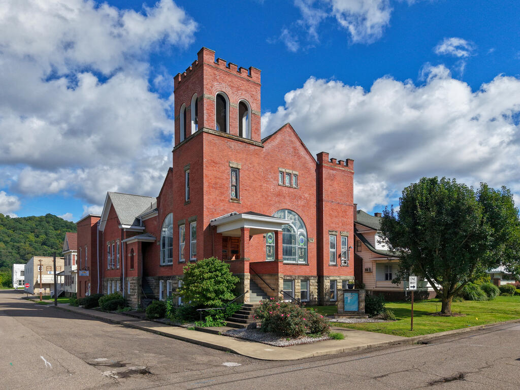 Red-brick building with a crenellated tower, stained-glass windows, and landscaped corner frontage.