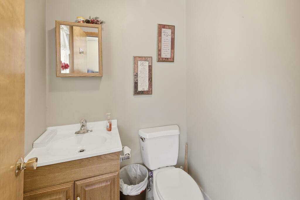Bathroom with a wood vanity, white sink and toilet, and framed wall decorations.