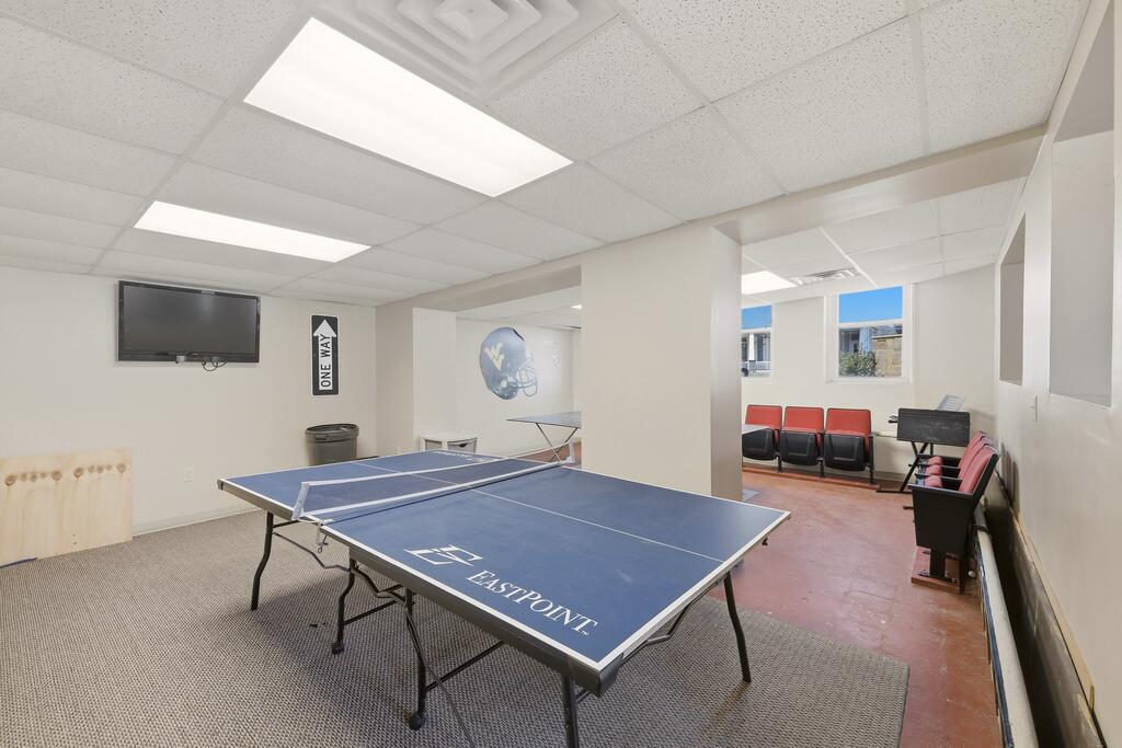 Recreation room with an Eastpoint ping-pong table, wall-mounted television, and red chairs.