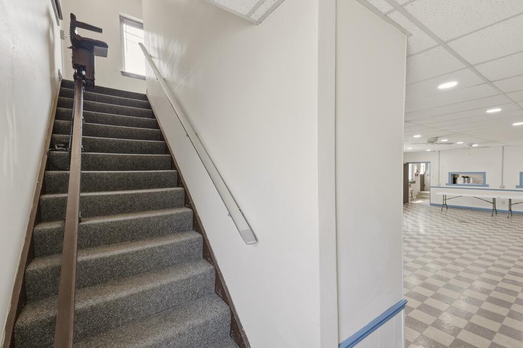 Carpeted staircase beside a tiled room with folding tables.