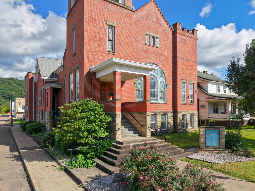 Red-brick church with stained-glass windows, broad front steps, and a Lighthouse Church sign.