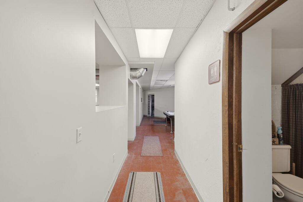 Interior hallway with red tile flooring and a bathroom doorway on the right.