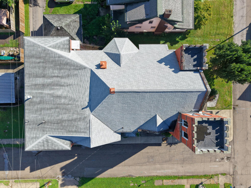 Aerial view of a red-brick building with a broad, multi-section gray roof.