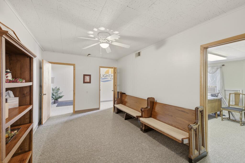 Carpeted interior room with wooden pew-style benches, built-in shelving, and open doorways.