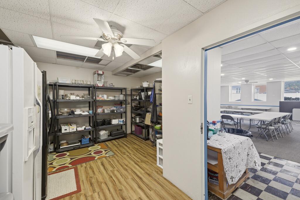 Storage and prep area with stocked shelving opens into a larger room with tables and chairs.