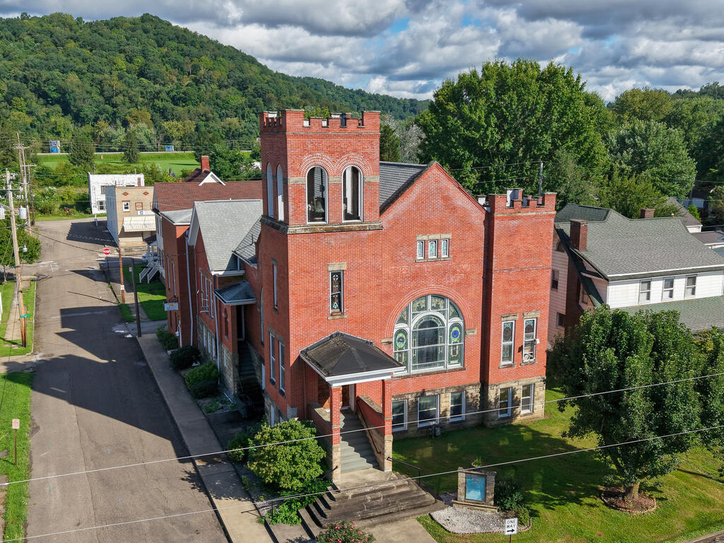 Red-brick building with crenellated towers and arched windows, viewed from above the front stairway.