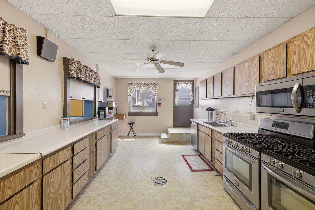 Long kitchen with wood-grain cabinets, stainless steel range, and an exterior door at the far end.