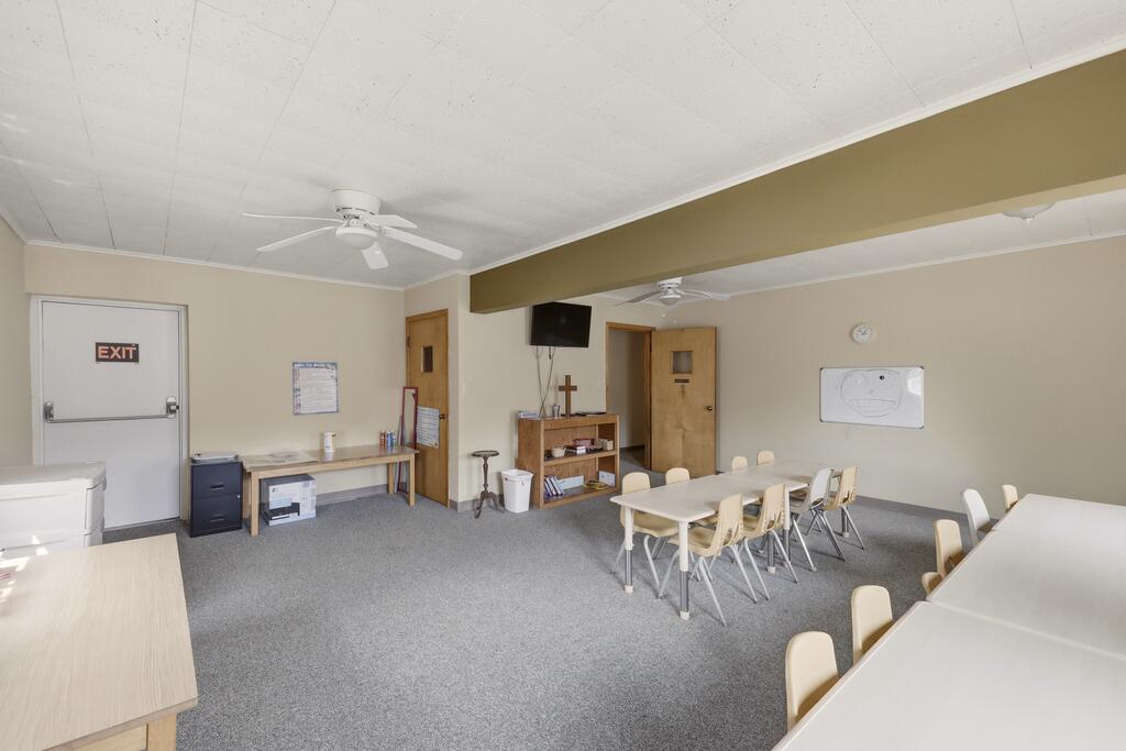 Meeting room with tables and chairs, gray carpet, and ceiling fans.