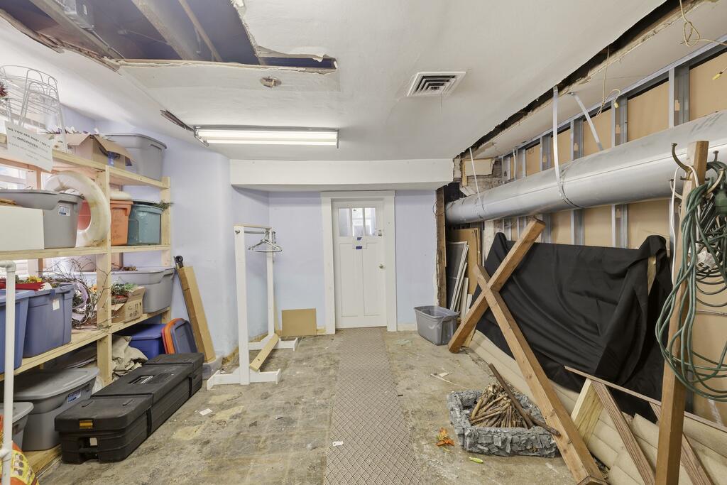 Basement storage room with cluttered shelves, exposed framing, and construction materials.