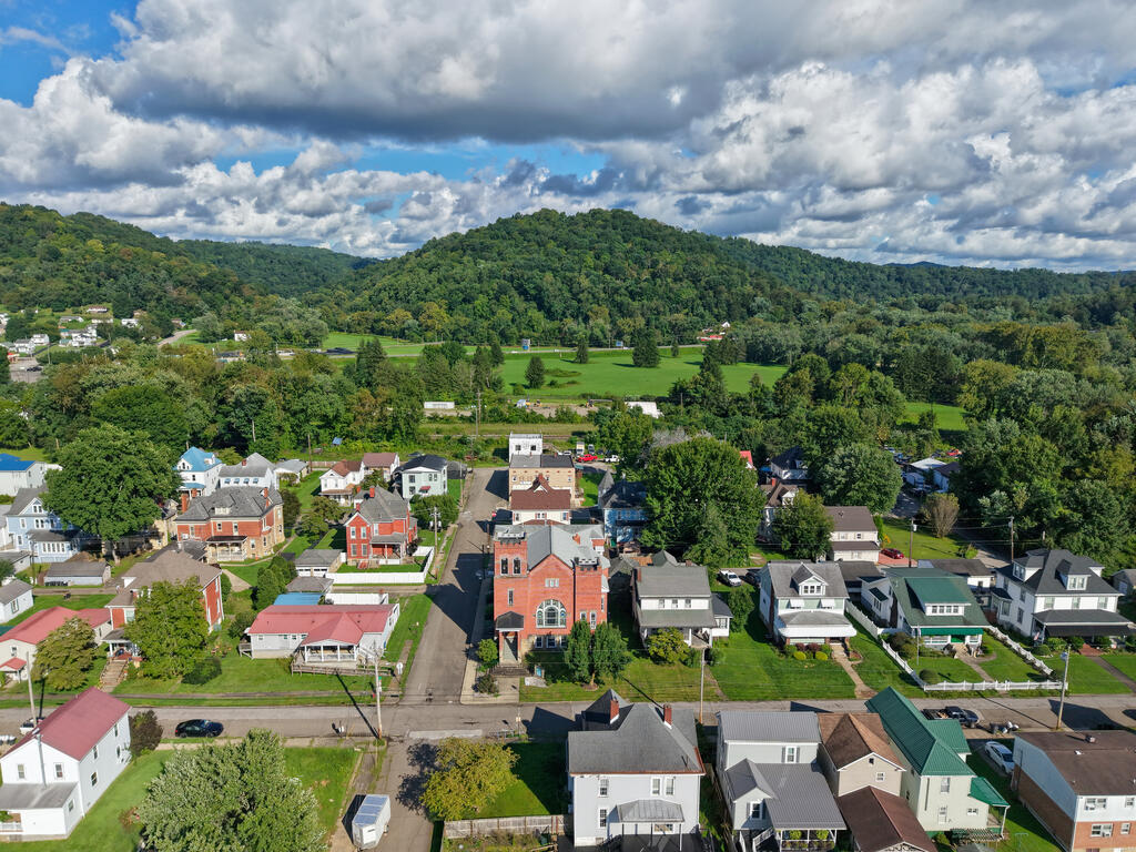 Aerial view of a residential neighborhood with a prominent red-brick building and forested hills.