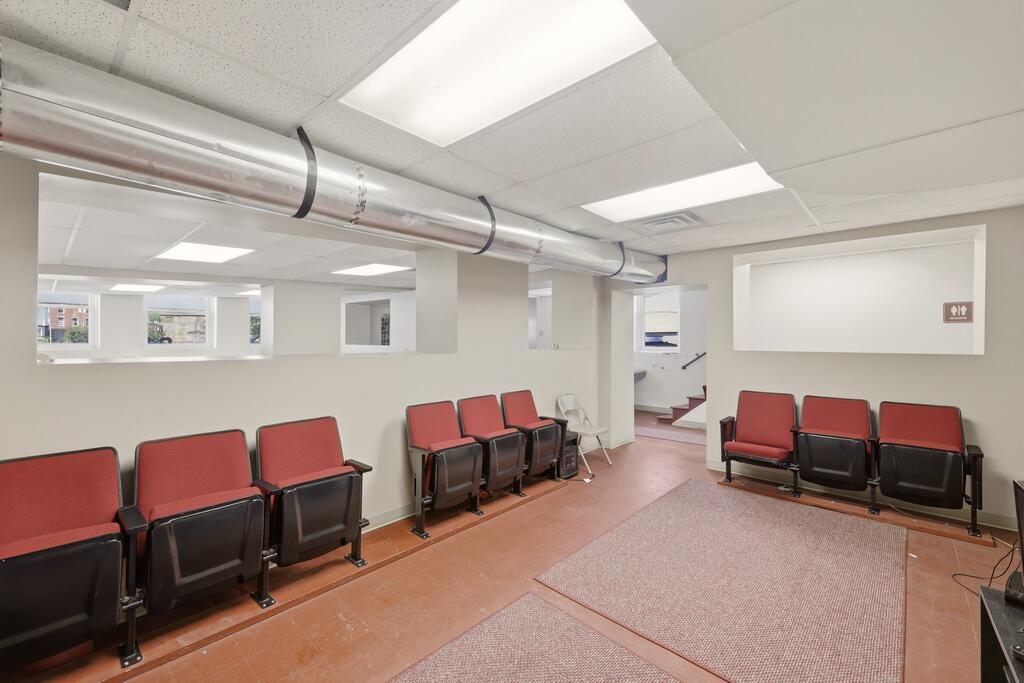 Waiting area with rows of red-and-black chairs and a carpeted floor section.