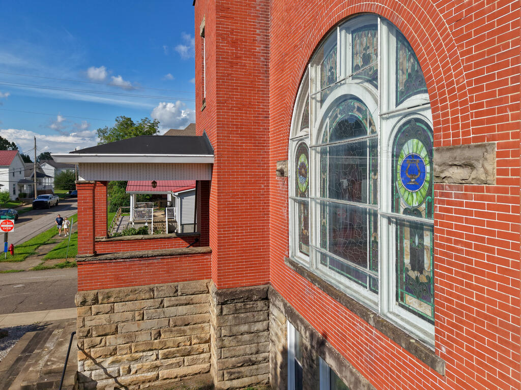 Red-brick building exterior with a large arched stained-glass window.