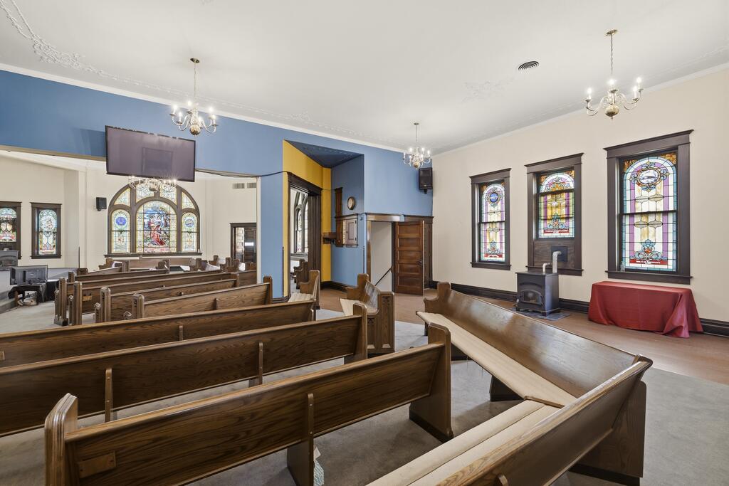 Church sanctuary with wooden pews, stained-glass windows, and blue accent walls.