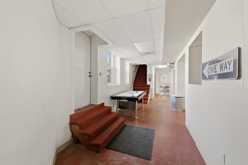 Hallway with a pool table, red-carpeted stairs, and a ONE WAY sign.
