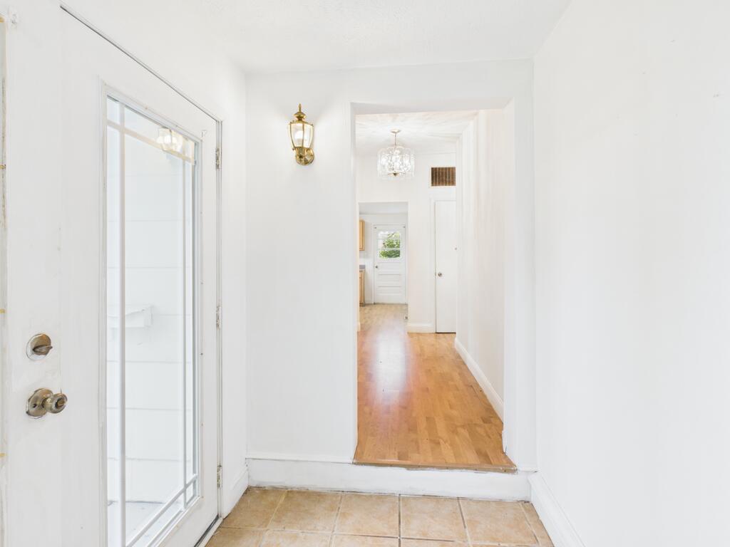Unfurnished entryway with tan tile leading to a long hardwood hallway.