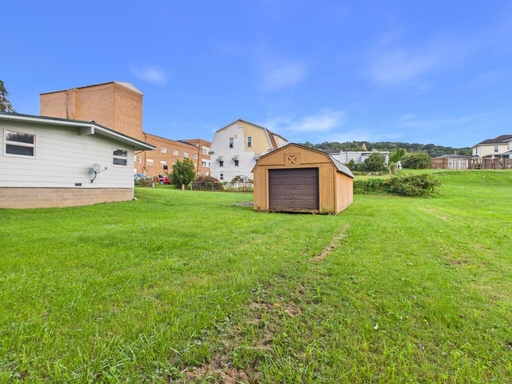 Wooden storage shed on a grassy yard beside the house.