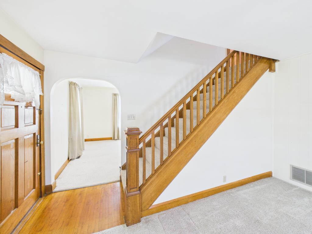 Entryway with a wooden staircase, hardwood flooring, and an arched doorway.