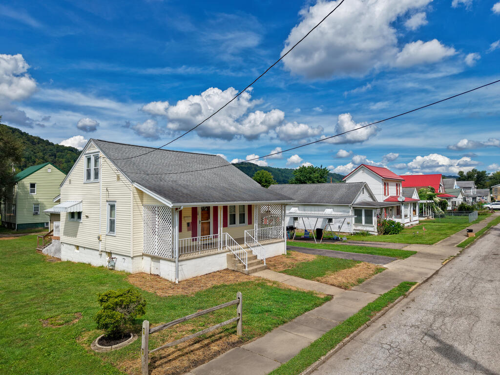 Light-colored house with a covered porch and lattice panels along a residential street.