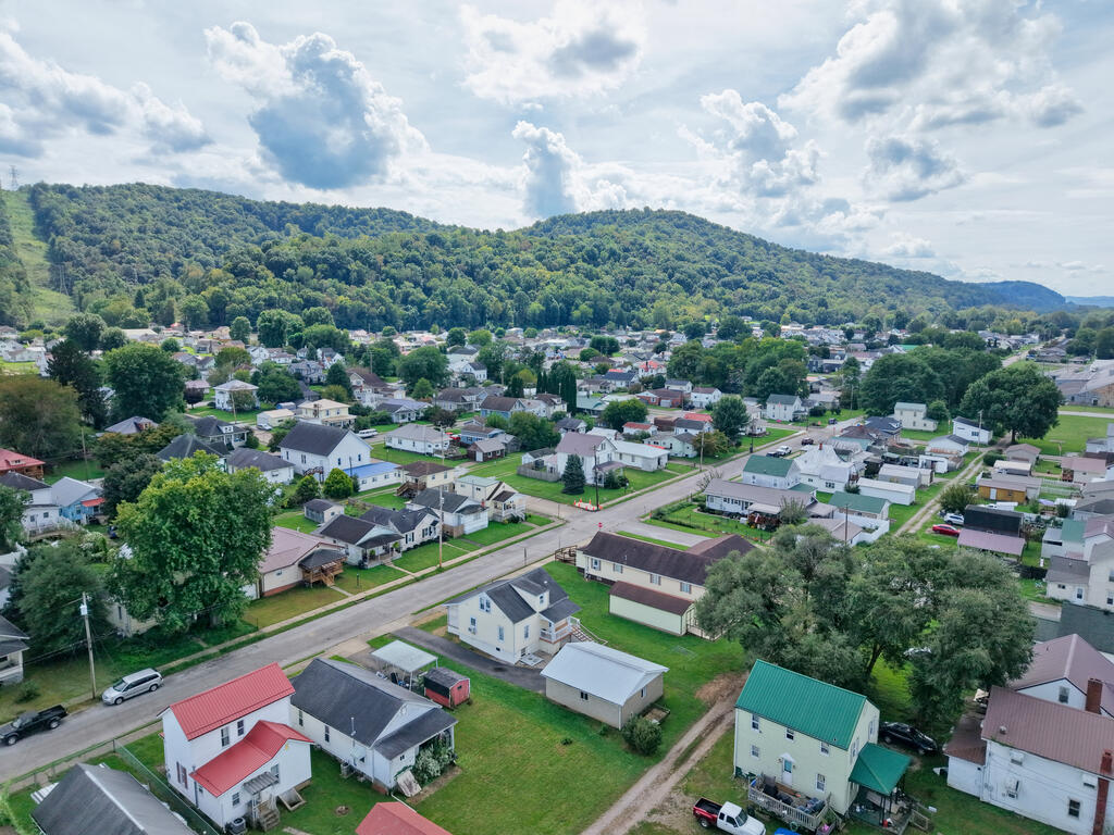 Aerial view of a residential neighborhood beneath wooded hills.