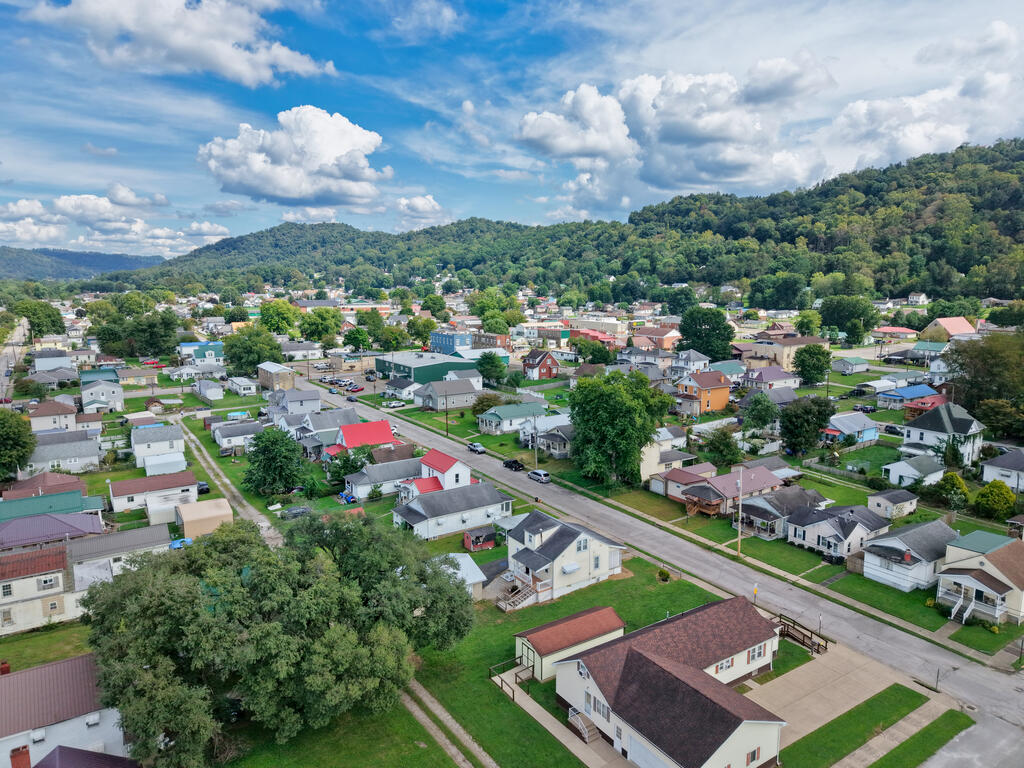 Aerial view of a small town, with residential streets and homes below wooded hills.